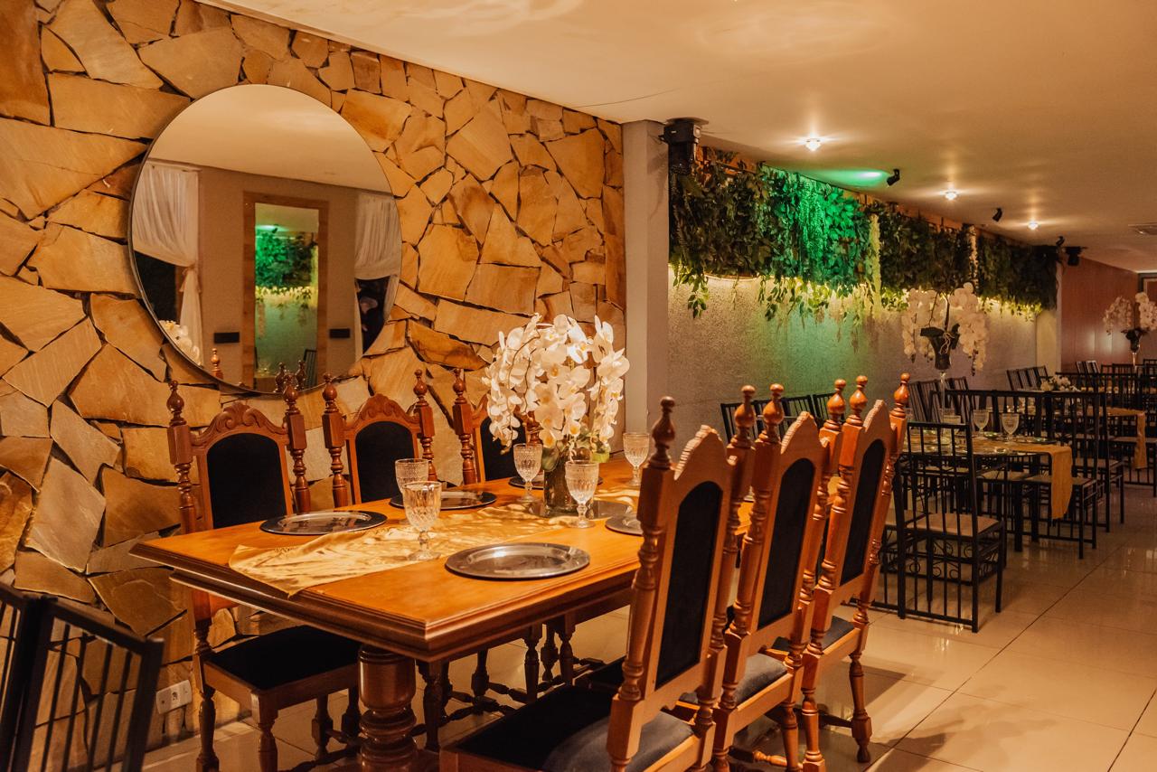 Ambiente com mesa de madeira, parede de pedra e jardim vertical no buffet em Guarulhos