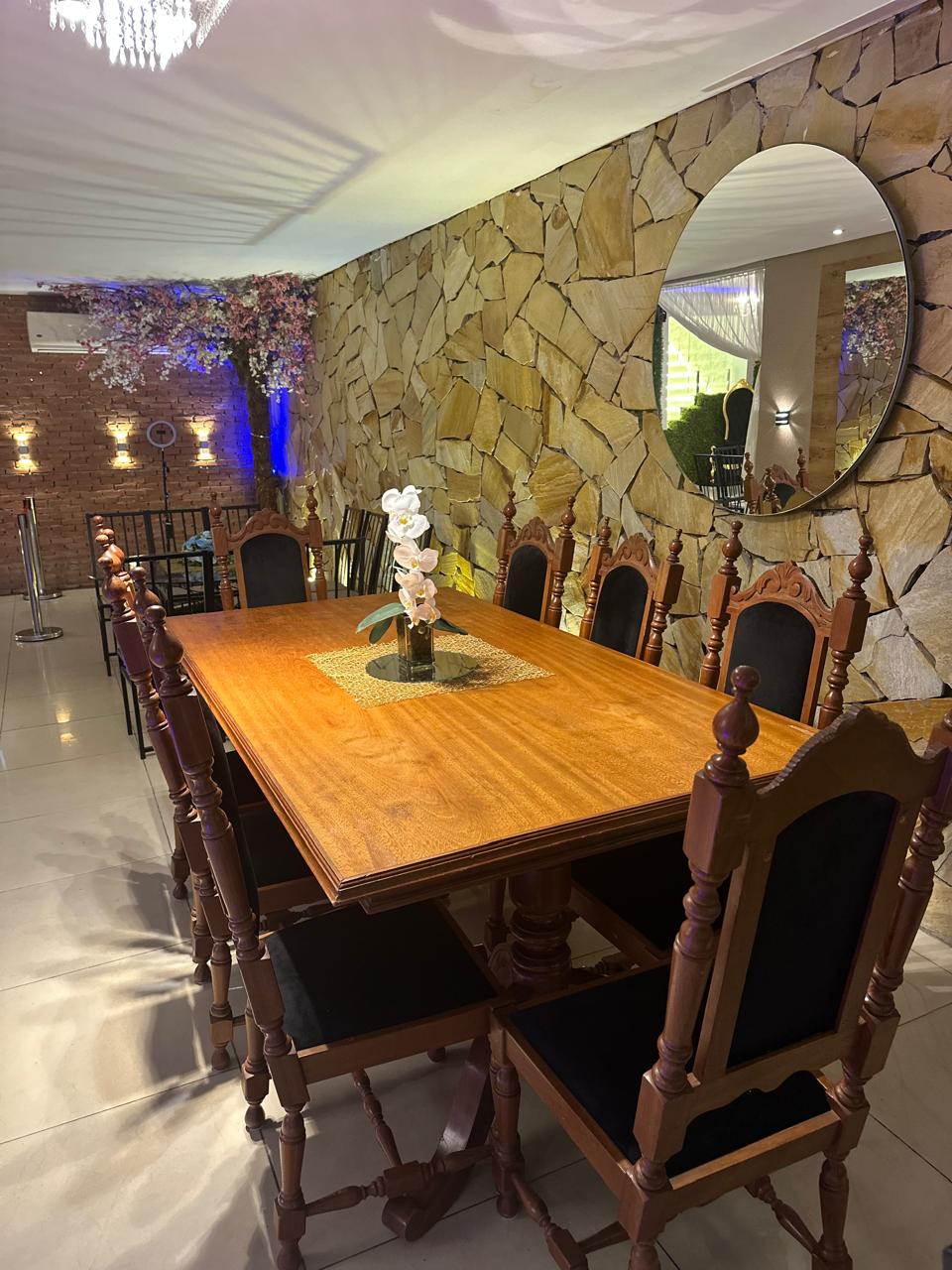 Mesa imperial de madeira com orquídeas em ambiente de parede de pedra em Guarulhos